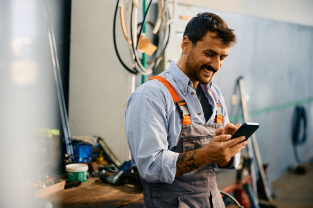 happy mechanic texting on cell phone while working in a garage. copy space.